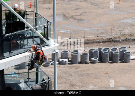 Un lavoratore edile abseils fino al 8 piano di Riverlight Quay Appartamento Edificio per praticare un foro. Nine Elms nel sud di Londra su 12/07/2017 Foto Stock