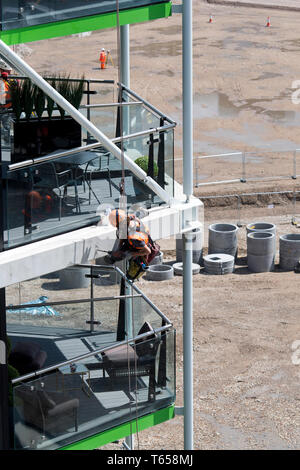 Un lavoratore edile abseils fino al 8 piano di Riverlight Quay Appartamento Edificio per praticare un foro. Nine Elms nel sud di Londra su 12/07/2017 Foto Stock