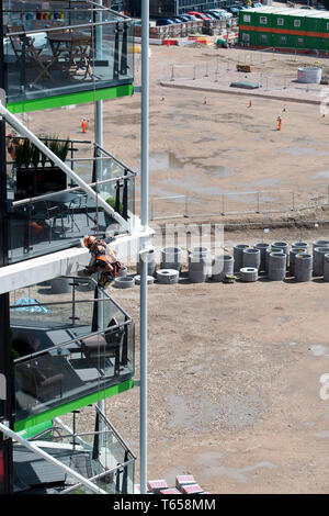 Un lavoratore edile abseils fino al 8 piano di Riverlight Quay Appartamento Edificio per praticare un foro. Nine Elms nel sud di Londra su 12/07/2017 Foto Stock