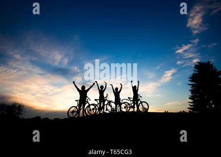 Sagome di ciclisti in Cielo di tramonto sullo sfondo. Foto Stock