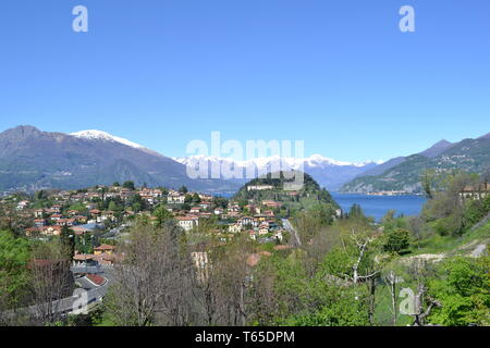 Bella vista della molla alla penisola di Bellagio con una città, Alpi europee con la neve su picchi e il lago di Como da strada a Lecco in una giornata di sole. Foto Stock