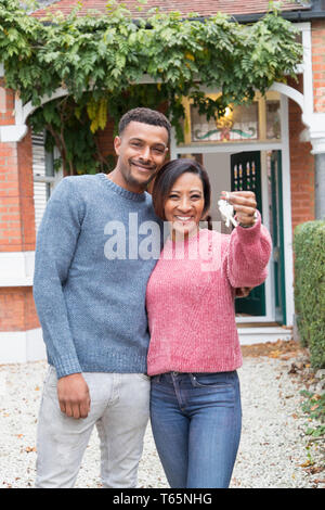 Ritratto felice coppia tenendo le chiavi di casa fuori casa nuova Foto Stock