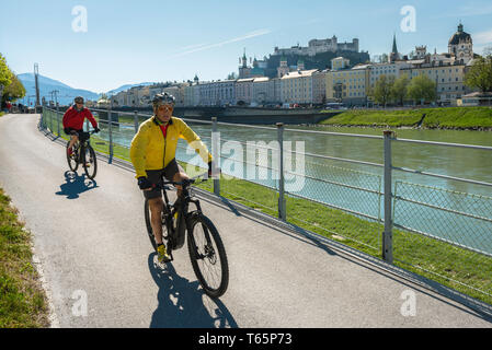 Escursioni in bicicletta Austria, vista su una mattinata estiva di mezza età giovane ciclismo su pista ciclabile lungo il fiume Salzach a Salisburgo, Austria. Foto Stock