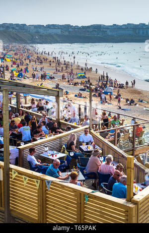 I villeggianti godendo il sole in un affollato Fistral Beach in Newquay in Cornovaglia. Foto Stock