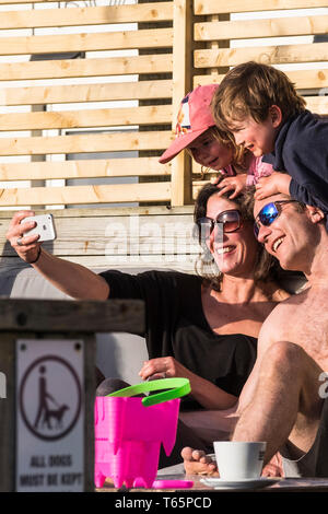 Una famiglia felice di vacanzieri prendendo un selfie con un iPhone in una soleggiata Fistral a Newquay in Cornovaglia. Foto Stock