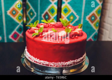 Deliziosa torta di lamponi con fragole, lamponi, mirtillo, ribes e pistacchi su sfondo di legno. Foto Stock