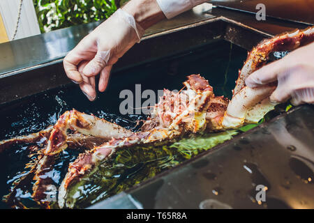 Chef di cucina ristorante in bianco uniforme è in possesso di fresco kamchatka grande granchio. Concetto di alimenti sani, stili di vita, utili a base di frutti di mare, delicatezza, dieta, in Foto Stock