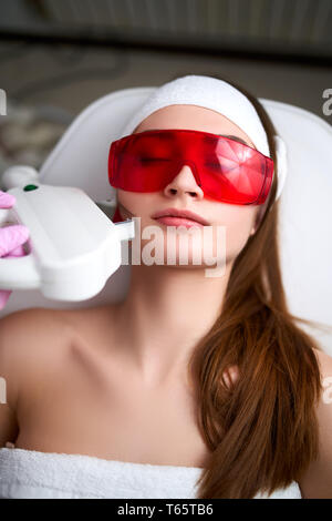Estetista medico facendo laser ringiovanimento RF per la bella giovane donna a un salone di bellezza. Elos cosmetologico capelli durante la procedura di rimozione. Viso estetici Foto Stock