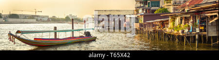 Vista panoramica di Bangkok riverside, Thailandia. Barca e baraccopoli su palafitte in primo piano. Panorama Foto Stock