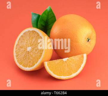 Frutta di arancia con fettine di arancia e foglie isolati su sfondo arancione. Foto Stock