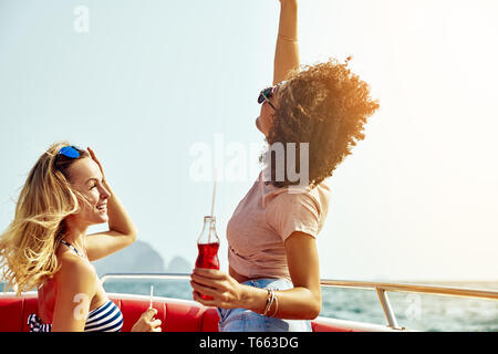 Due carefree giovani amici avente un buon tempo insieme su una barca in mezzo al mare durante le vacanze estive Foto Stock