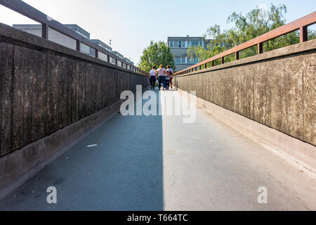 Una famiglia a piedi lungo una passerella di calcestruzzo strada ponte costruito negli anni settanta seguenti tendenze architettoniche del tempo Foto Stock