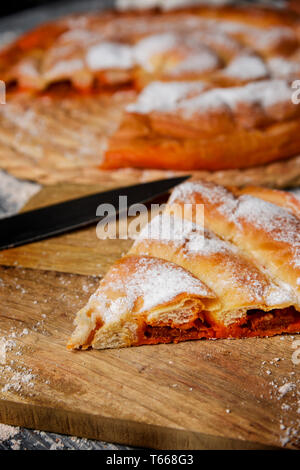 Primo piano di un pezzo di, la ensaimada, un tipico di Mallorca, Spagna, riempito con sobrassada, su una tavola in legno rustico Foto Stock