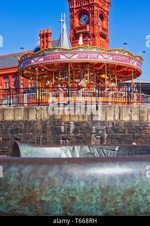 Bronzo anello celtico scultura con fiera carosello e l'Edificio Pierhead in background, la Baia di Cardiff, Cardiff Wales, Regno Unito Foto Stock