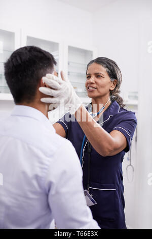 Medico donna esame paziente di sesso maschile in clinica sala esame Foto Stock