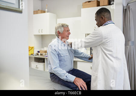 Maschio esame medico paziente senior in clinica sala esame Foto Stock