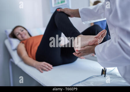 Medico esaminando gamba del paziente di sesso femminile nella sala esame Foto Stock