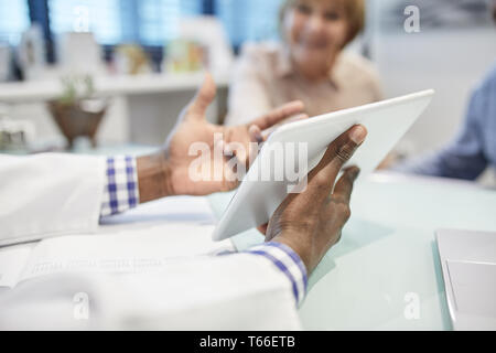 Medico con tavoletta digitale a parlare con il paziente in ufficio medici Foto Stock