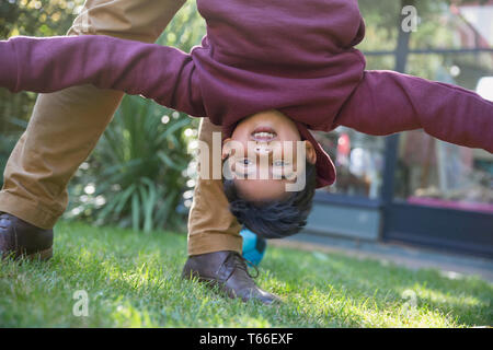 Giocoso ragazzo appeso a testa in giù Foto Stock