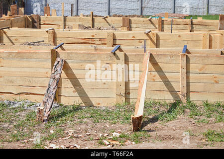 Casseforme in legno, base in nastro di calcestruzzo per un cottage. Primo piano di casseforme in legno con rinforzi in acciaio per la preparazione della lastra Foto Stock