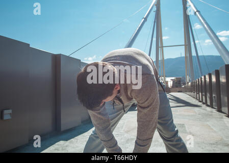 Un uomo è in esercizio su strada e preparare per il jogging Foto Stock