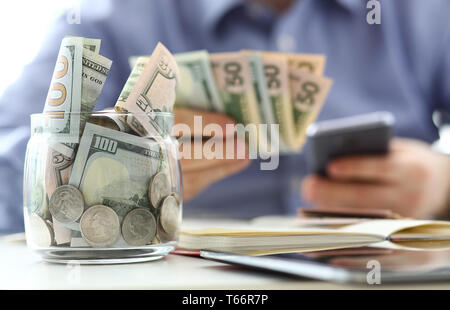 Ricca vaso pieno o noi le banconote e le monete in euro con bracci di imprenditore in background Foto Stock