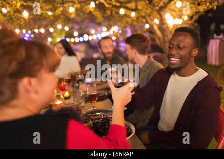 Happy amici tostare bicchieri da vino godendo la cena party in giardino Foto Stock