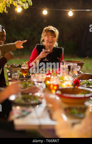 Donna felice ridendo, godendo la cena party in giardino con gli amici Foto Stock
