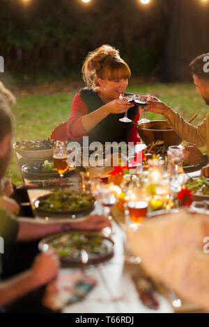 Happy amici la tostatura del vino a cena party in giardino Foto Stock