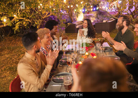 Amici battimani, godendo la cena party in giardino Foto Stock