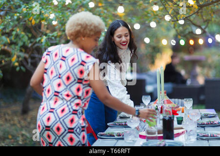 Le donne amici nella tabella di impostazione per la cena party in giardino Foto Stock