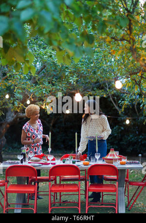 Le donne amici nella tabella di impostazione per la cena party in giardino Foto Stock