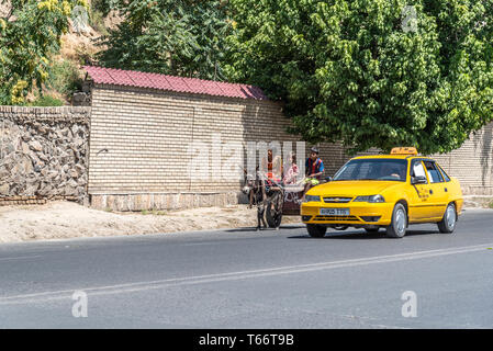 Una famiglia su un asino carrello è passata da un Taxi a Samarcanda, Uzbekistan Foto Stock