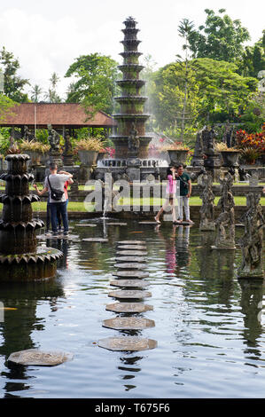 I turisti sulle pietre miliari presso la Taman Tirtagangga (l'acqua Royal Palace e Giardini) a Bali, in Indonesia Foto Stock