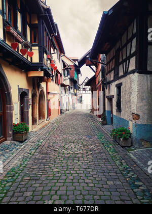 Strade strette del vecchio villaggio di Eguisheim con mezzo in legno case medievali lungo la famosa strada del vino in Alsazia, Francia. Foto Stock