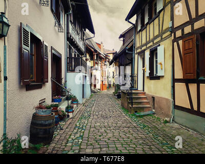 Strade strette del vecchio villaggio di Eguisheim con mezzo in legno case medievali lungo la famosa strada del vino in Alsazia, Francia. Foto Stock