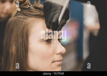 Professional Make Up Artist facendo fare fino in un salone di bellezza. Colorazione sopracciglia. vernici master sopracciglia con henna a bella ragazza, vernici con spazzola in s Foto Stock