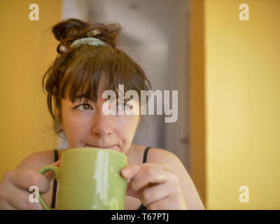 Triste e sleepy giovane donna attraente con una tazza di caffè al mattino a casa Foto Stock