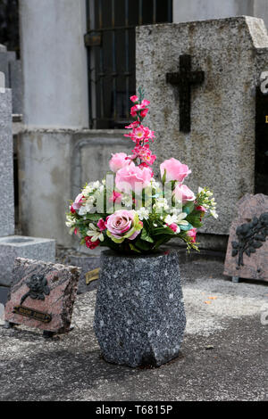 Fleurs dans un vase en granit sur une pierre tombale. Foto Stock