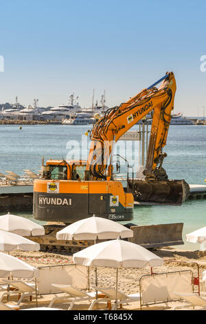 CANNES, Francia - Aprile 2019: Escavatore aggiunta di nuova sabbia della spiaggia di Cannes pronta per la primavera e l'estate stagione di vacanze Foto Stock