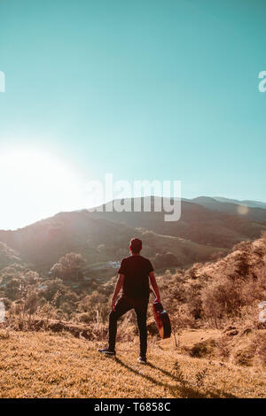 Uomo con chitarra in montagna in una giornata di sole Foto Stock