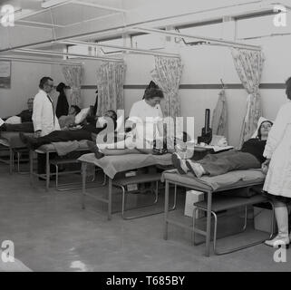 1973, storico, i membri del pubblico in un centro sanitario locale giacenti sui banchi della donazione di sangue, Londra, Inghilterra. Foto Stock