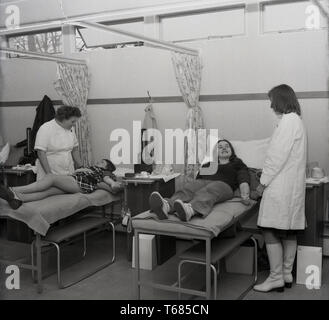 1973, storico, i membri del pubblico nel centro sanitario locale giacente su coperte sui banchi della donazione di sangue, Londra, Inghilterra. Foto Stock