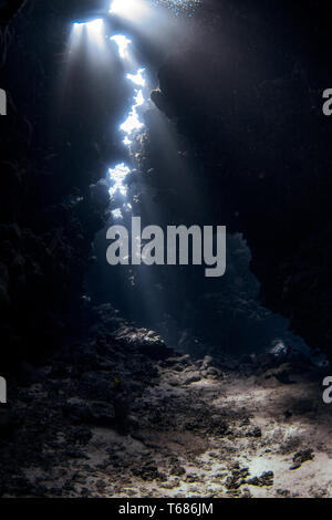 Luce brilla in attraverso il tetto di una grotta sottomarina Foto Stock