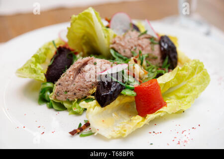 Insalata di Creative con prugne e pasta di pesce sulla piastra, close-up Foto Stock