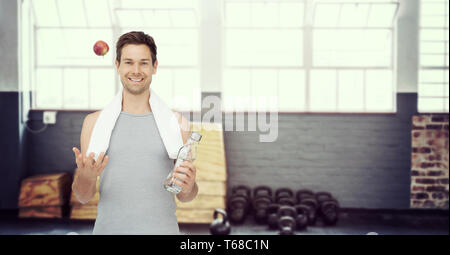 Immagine composita di sorridere montare giovane con Apple e una bottiglia d'acqua Foto Stock