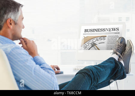 Immagine composita di rilassante uomo con piedi sulla scrivania utilizzando il computer Foto Stock