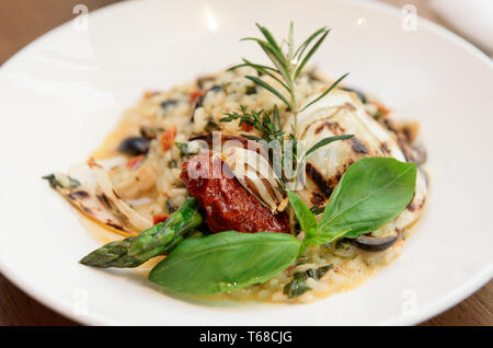 Risotto con i pomodori secchi e le erbe nella piastra, close-up Foto Stock