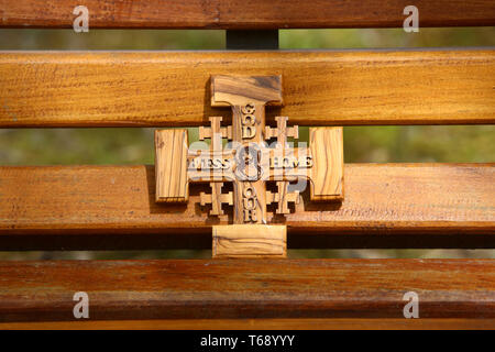 Croix de Jérusalem en bois d'olivier représentant Jésus-Christ sur onu banc en bois. Foto Stock