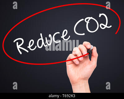 Man mano che scrive di ridurre le emissioni di CO2 con pennarello nero su schermo visivo. Foto Stock